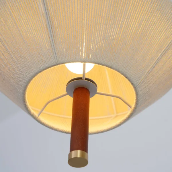 Underside of the thread pendant light showing the glowing bulb, white frame and wood stem with a brass end cap