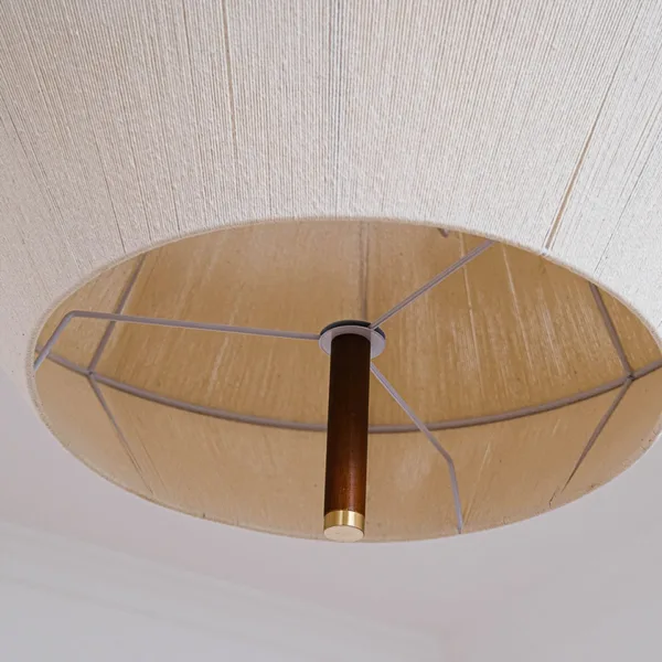 Inside of the thread pendant light shade showing the white wire frame and the central wood stem with brass cap