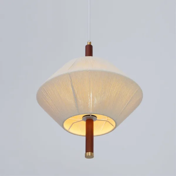 Thread-wound pendant light lit from below, showing the warm glow inside the cream shade and the wood stem with brass cap