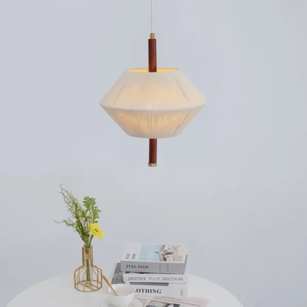 Thread-wound diamond pendant light hanging above a round table with books and a flower vase
