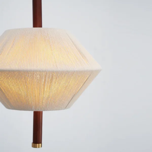 Close-up of the thread pendant light glowing with warm light shining through the wound cream thread