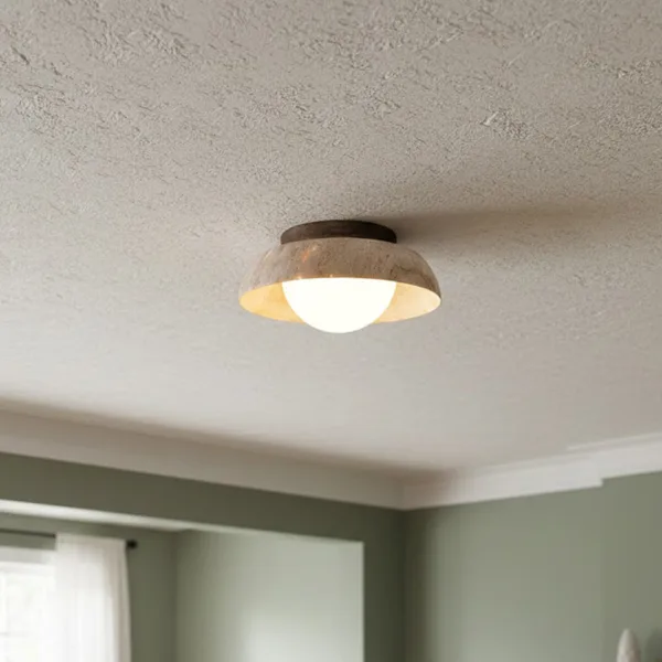 Small travertine flush mount light on a textured bedroom ceiling