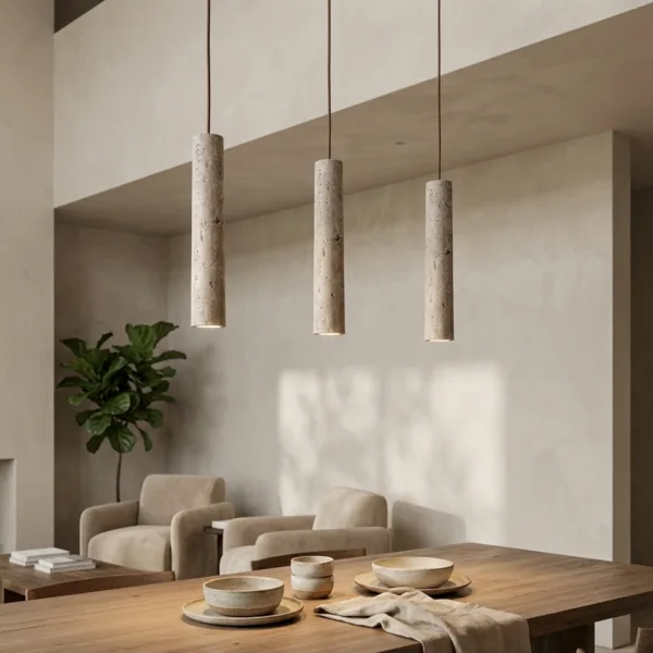 Three travertine cylinder pendant lights hanging over a long wooden dining table