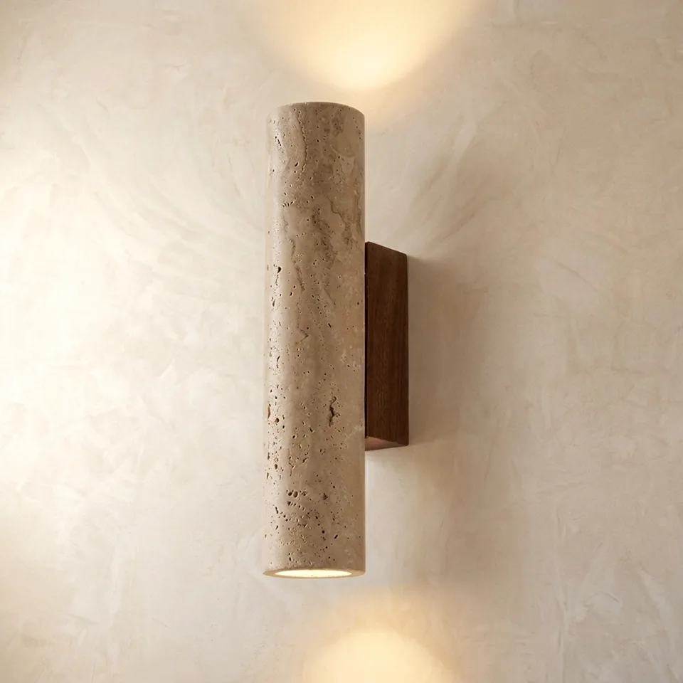 Travertine cylinder wall light on a wood backplate, glowing up and down on a plaster wall