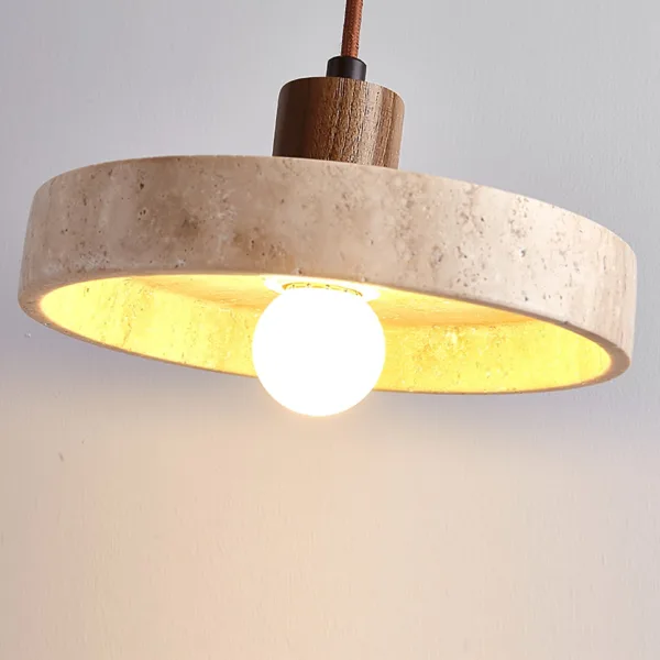 Close-up of the travertine disc pendant light showing the golden stone glow under the shade
