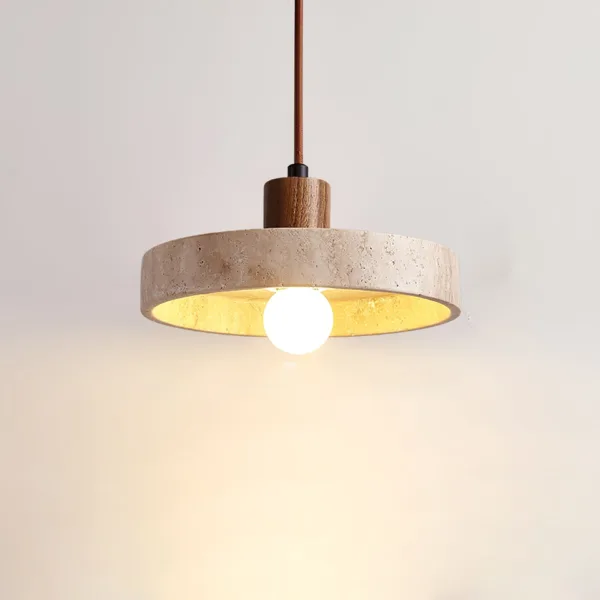 Natural travertine stone pendant light with a wood cap and brown fabric cord, lit