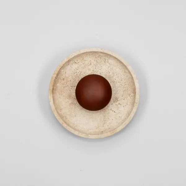 Travertine round wall lamp lit, showing the glowing ring on the cream stone