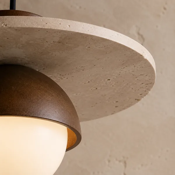 Close-up of the travertine dome pendant light: honed travertine disc with natural pits above the wood dome and lit globe