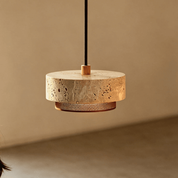 Travertine mini pendant light on a black cord showing the pitted stone drum and glowing perforated ring