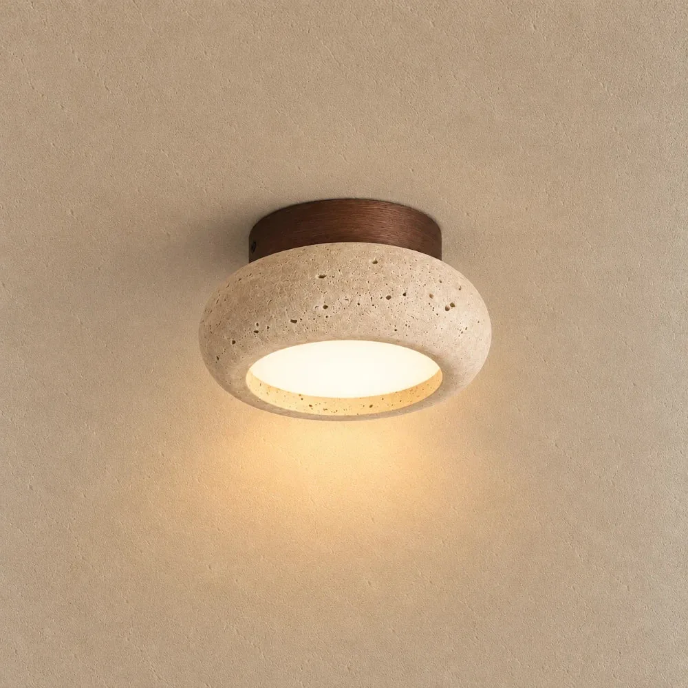 Foyer ceiling light in real travertine on a walnut-tone wood canopy, glowing warm on a plaster ceiling