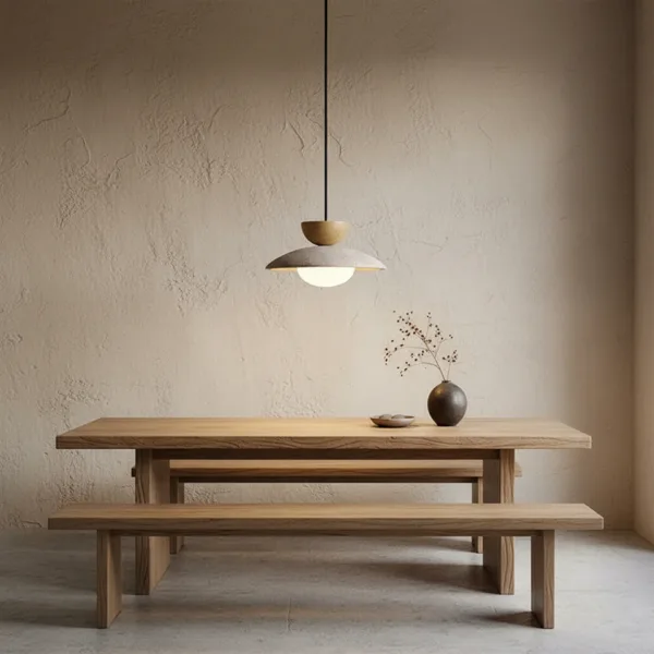 Travertine globe pendant light hanging over a solid wood dining table and benches in a minimalist plaster room