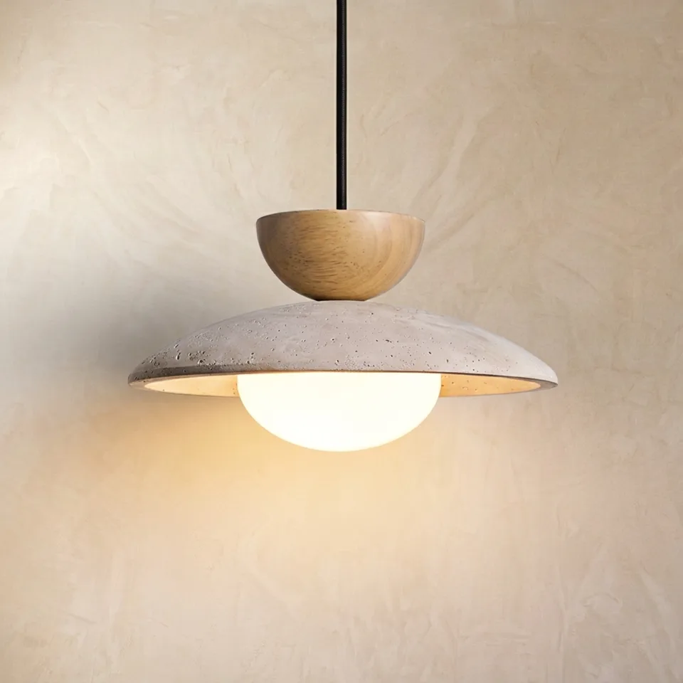 Travertine globe pendant light with a wood half-dome cap and opal glass globe glowing against a plaster wall