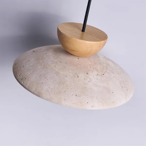 Top of the travertine globe pendant light showing the pitted stone shade and wood half-dome cap