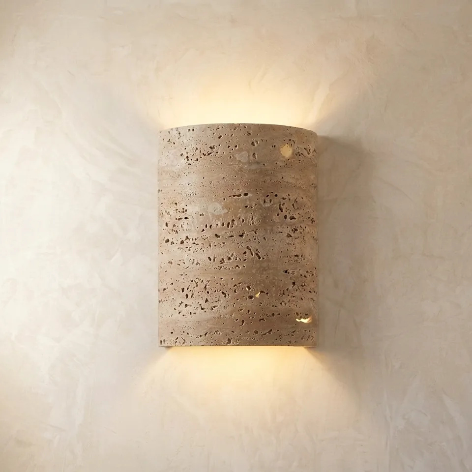 Travertine half-cylinder wall light glowing up and down on a plaster wall