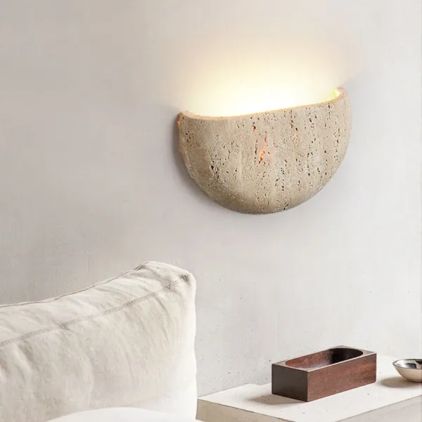Travertine half-moon moon wall light glowing above a bed with white linen pillows