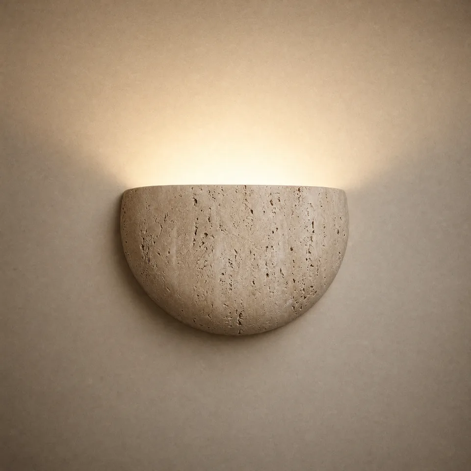 Travertine half-moon wall sconce washing warm light up a plaster wall