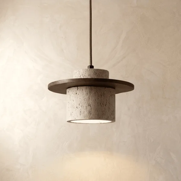 Travertine pendant light lit, a pitted cream stone cylinder under a dark wood disc glowing against a plaster wall
