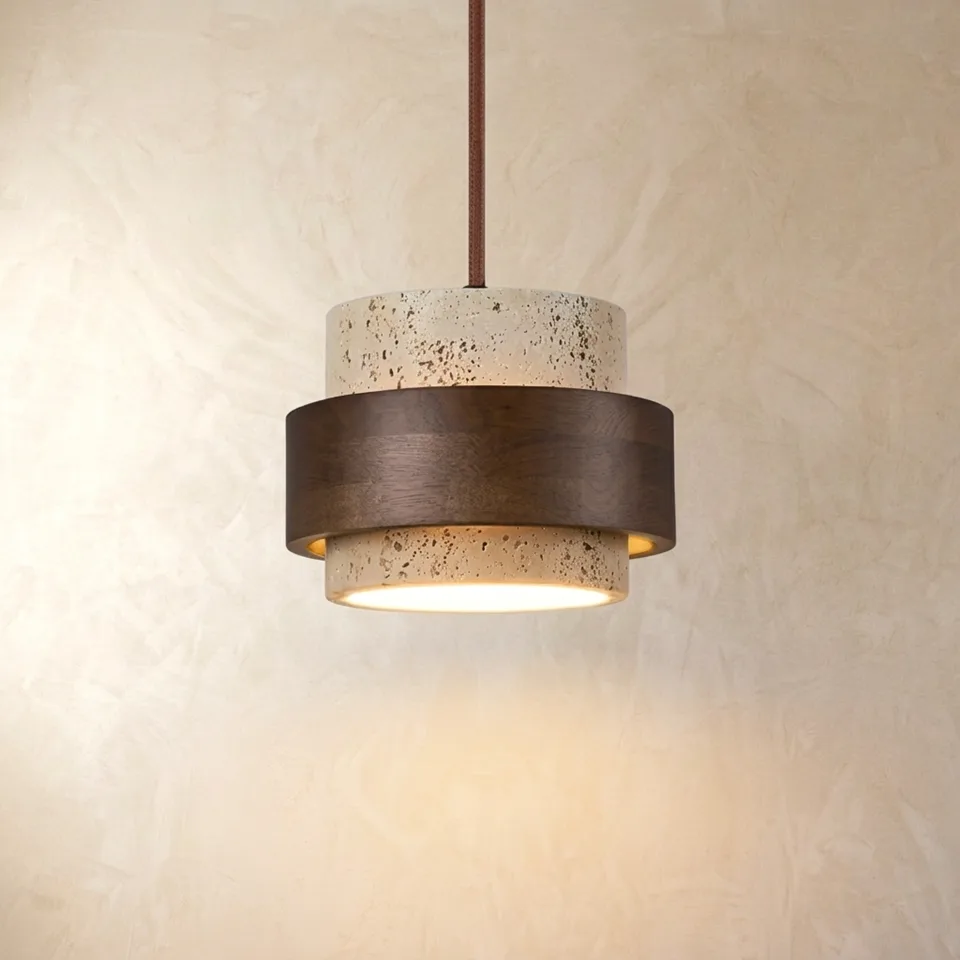 Travertine and wood tiered pendant light with a dark wood band glowing warmly against a plaster wall
