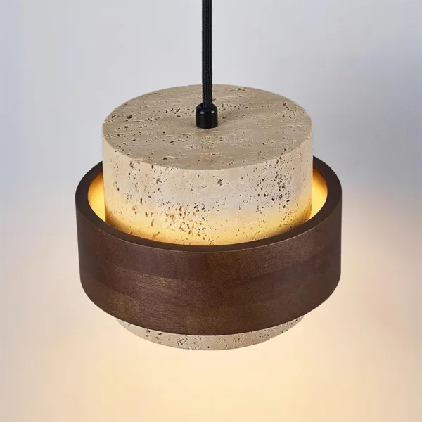 Top view of the travertine and wood pendant light showing the pitted travertine cylinder, black cord grip and glow inside the wood band