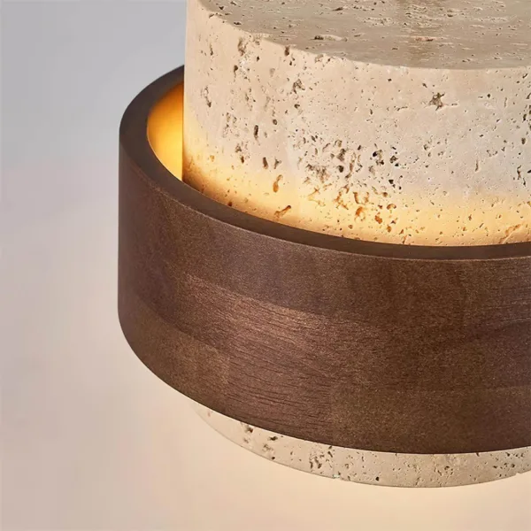 Close-up of the dark wood band on the travertine and wood pendant light, with warm light glowing on the pitted stone