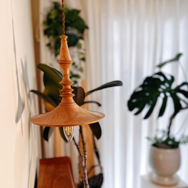 Close-up of the turned rings and brim of the wooden pendant light with a filament bulb