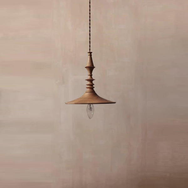 Turned wood spindle pendant light with a flared brim and glowing bulb against a plaster wall