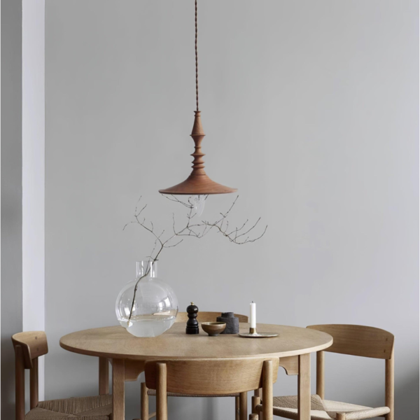 Turned wood pendant light over a round oak dining table