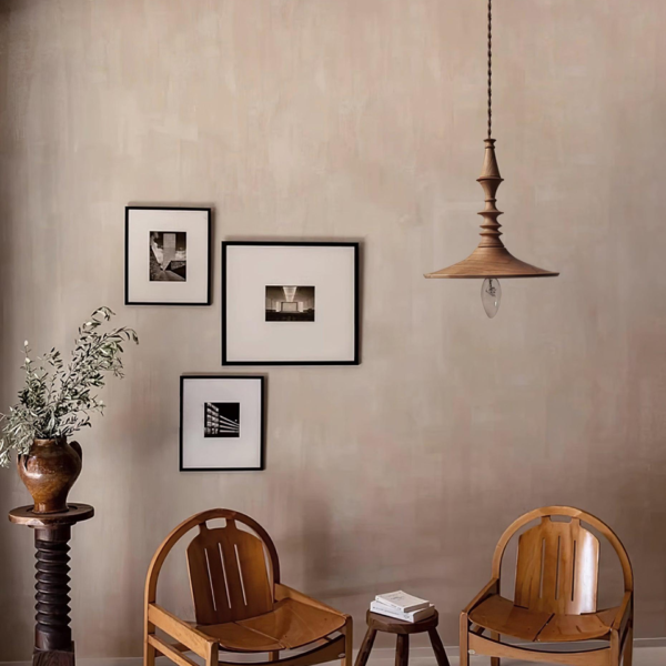Turned wood pendant light above two wooden chairs and framed prints