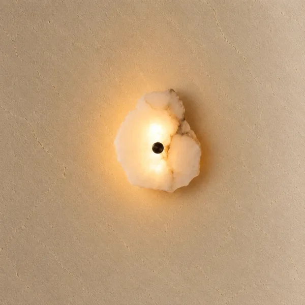 Raw-edge alabaster slab wall light glowing honey-warm on a textured beige plaster wall
